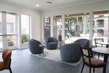 A room with a table and chairs and a view of a pool outside.